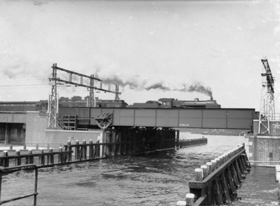 220194 Gezicht op de spoorbrug over het Oosterdok te Amsterdam, met een passerende trein getrokken door een ...
